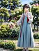 A woman in a blue dress standing in a garden.