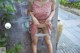 A woman in a pink dress sitting on a wall.