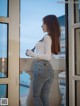 A woman standing on a balcony looking out a window.