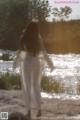 A woman in a white dress is walking by the water.