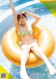 A woman in a bikini sitting on an inflatable ring in a pool.