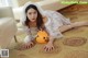 A woman in a white dress laying on the floor next to a pumpkin.