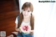A young woman holding a slice of watermelon with a spoon.