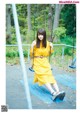 A woman in a yellow dress sitting on a swing.